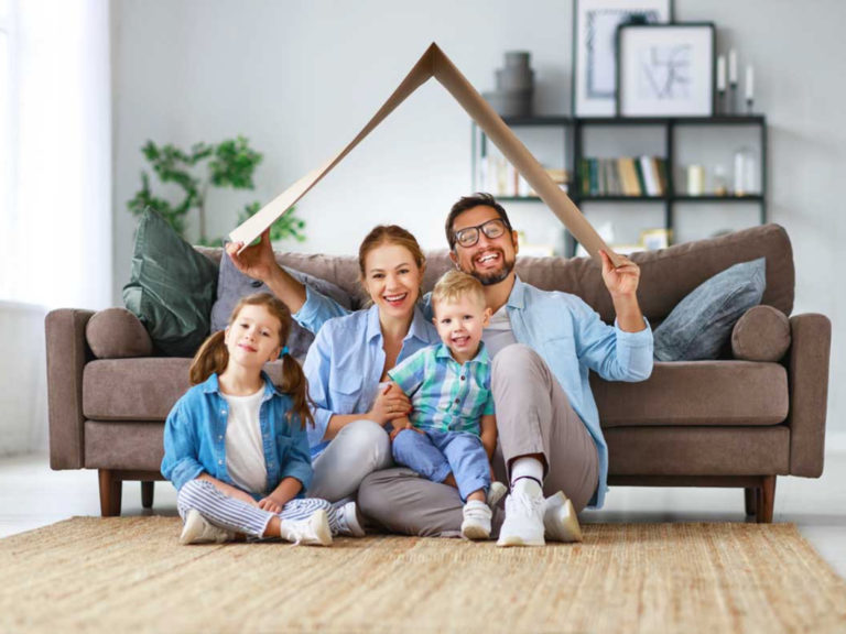 Famille assise par terre devant un canapé